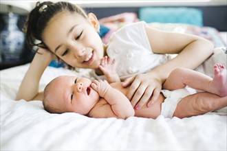Girl (10-11) lying in bed beside brother (2-5 months)