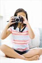 Sitting girl  (10-11) holding  camera and taking photo