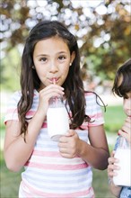 Girl (10-11) and boy (6-7)   in park drinking milk