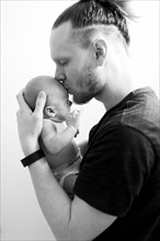 Father kissing newborn son (0-1 months)