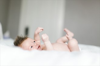 Naked baby girl (0-1 months) lying on bed