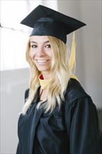 Portrait of young blond woman wearing graduation gown