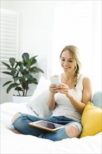 Young woman with mobile phone sitting on sofa