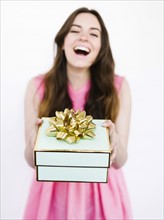 Mid adult woman holding gift box and laughing