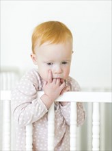 Portrait of girl ( 12-17 months ) holding fingers in mouth