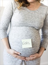 Portrait of smiling pregnant woman with adhesive note on belly