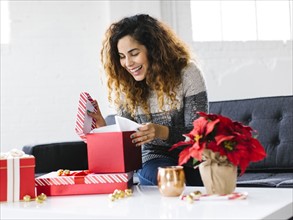 Happy woman on sofa opening Christmas gift