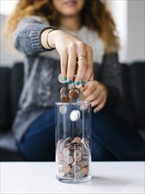 Woman dropping coins into glass container