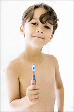 Boy (6-7) holding toothbrush