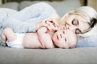Mother with newborn (0-1 months) lying on sofa