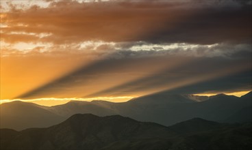 USA, Colorado, Denver, Setting sun shining through clouds over Front Range