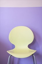 Empty yellow chair by purple wall