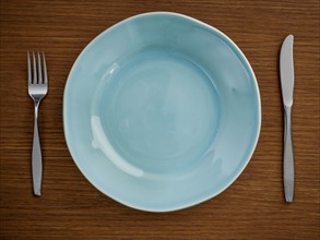 Studio shot of blue plate with fork and knife