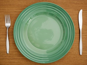 Studio shot of green plate with fork and knife