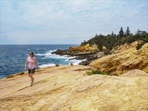 Australia, New South Wales, Bermagui, Woman walking on coast