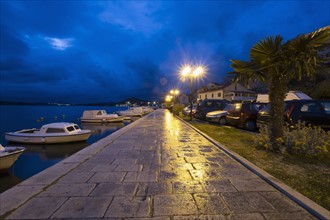 Croatia, Dalmatia, Sibenik, Empty sidewalk by harbor at dusk