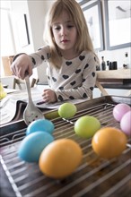 Girl (4-5) making colored Easter eggs