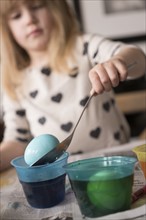 Girl (4-5) making colored Easter eggs
