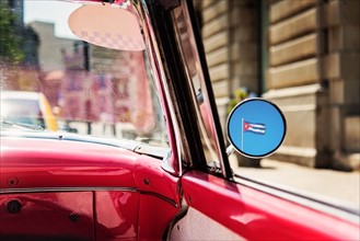 Cuba, Havana, Cuban flag reflecting in mirror of convertible