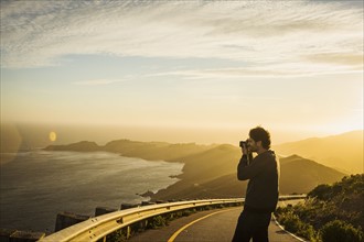 USA, California, San Francisco, California, Silhouette of man photographing coastline at sunset