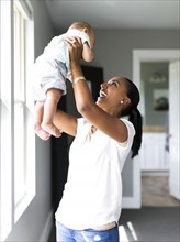 Mother holding aloft baby boy (2-5 months)