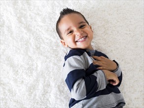 Boy (2-3) lying down on carpet and laughing