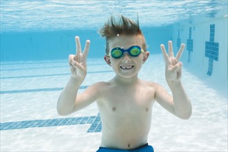 Portrait of boy (6-7) gesturing in swimming pool