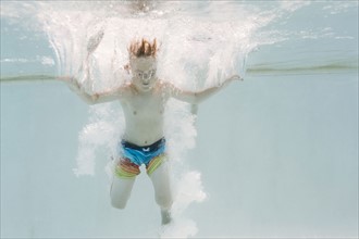 Boy (6-7) jumping into swimming pool