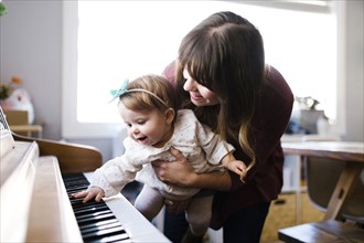 Mother with daughter (12-17 months) playing piano