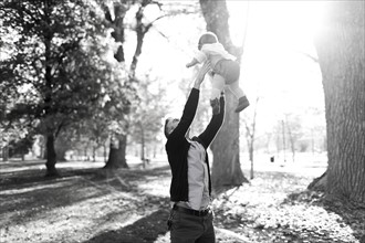 Father throwing daughter (12-17 months) up in air in park
