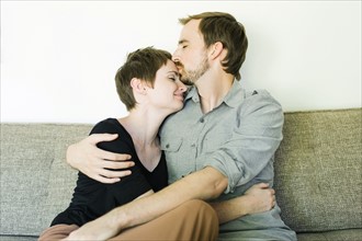 Couple embracing and kissing on sofa