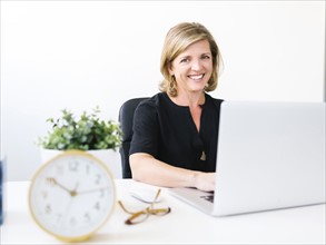 Woman using laptop, looking at camera