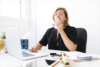Woman using laptop and sneezing