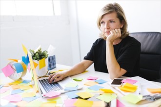 Mature woman at office overwhelmed by adhesive notes