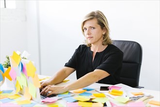 Portrait of Mature woman at office overwhelmed by adhesive notes
