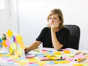 Portrait of Mature woman at office overwhelmed by adhesive notes