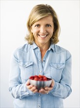 Portrait of Mature woman holding bowl with raspberries