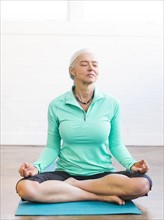 Senior woman meditating on mat