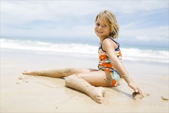Girl (6-7) sitting on beach