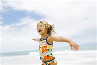 Girl (6-7) spinning on beach