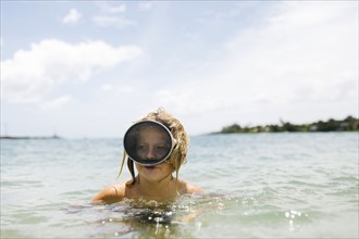 Boy (8-9) wearing swimming goggles standing in sea