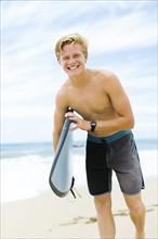 Man standing on beach and holding surfboard