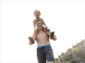 Young man carrying brother on shoulders