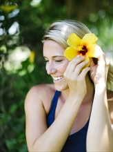 Blonde beautiful woman decorates hair with flower