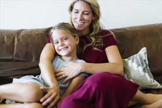 Woman sitting with daughter (6-7) on couch