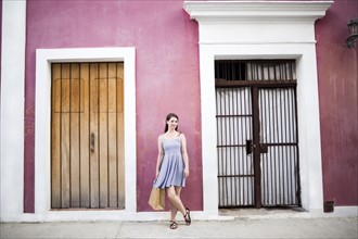 Puerto Rico, San Juan, Woman with shopping bag standing in front of pink building