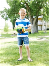 Young boy (6-7) with baseball glove standing in park