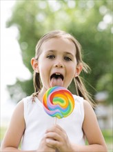 Girl (4-5) licking colorful lollipop