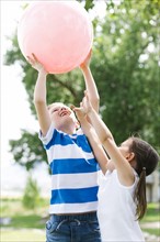 Boy (6-7) and girl (4-5) holding pink ball