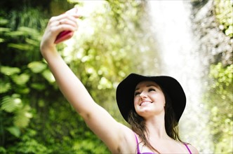 Smiling woman taking selfie with waterfall in background